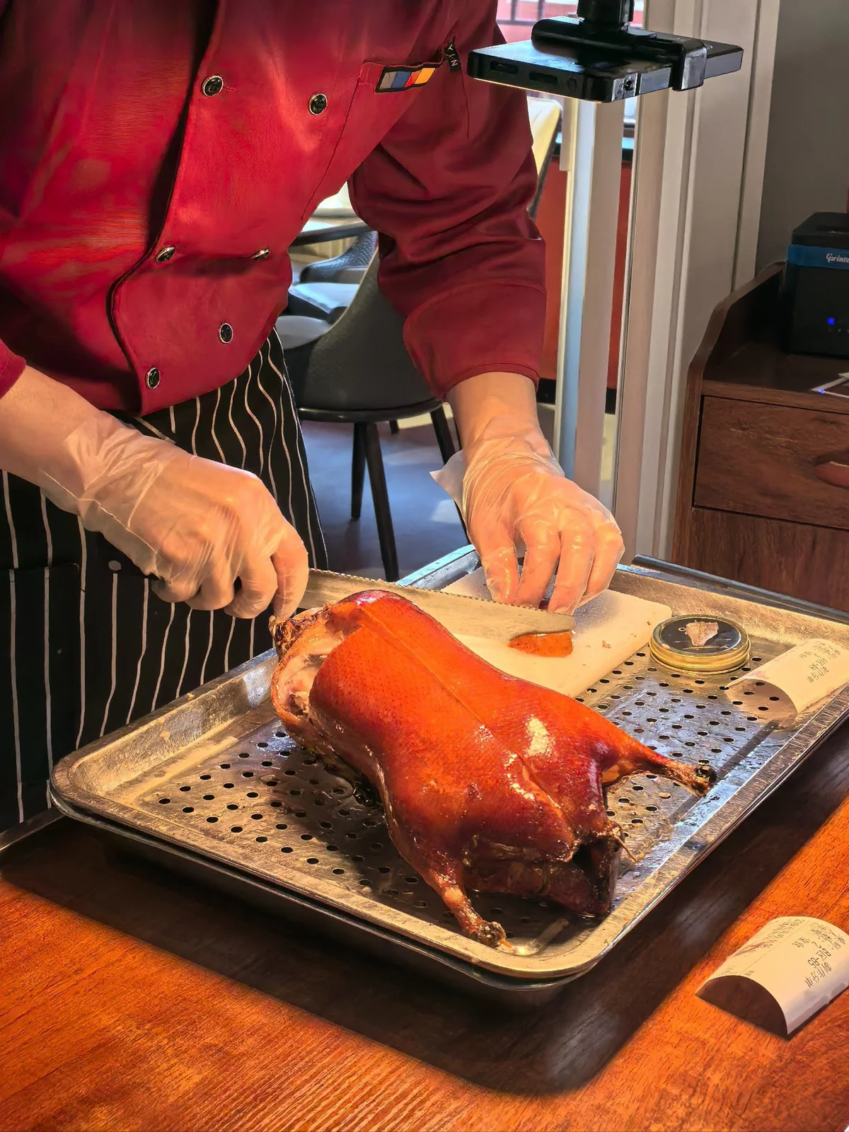 A chef carving freshly roasted Peking Duck on a cutting board.
