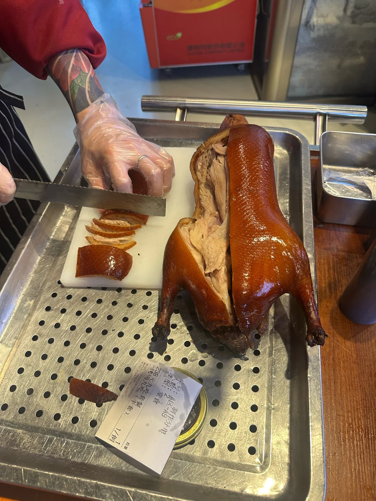 A chef presenting a whole roasted Peking Duck before carving.