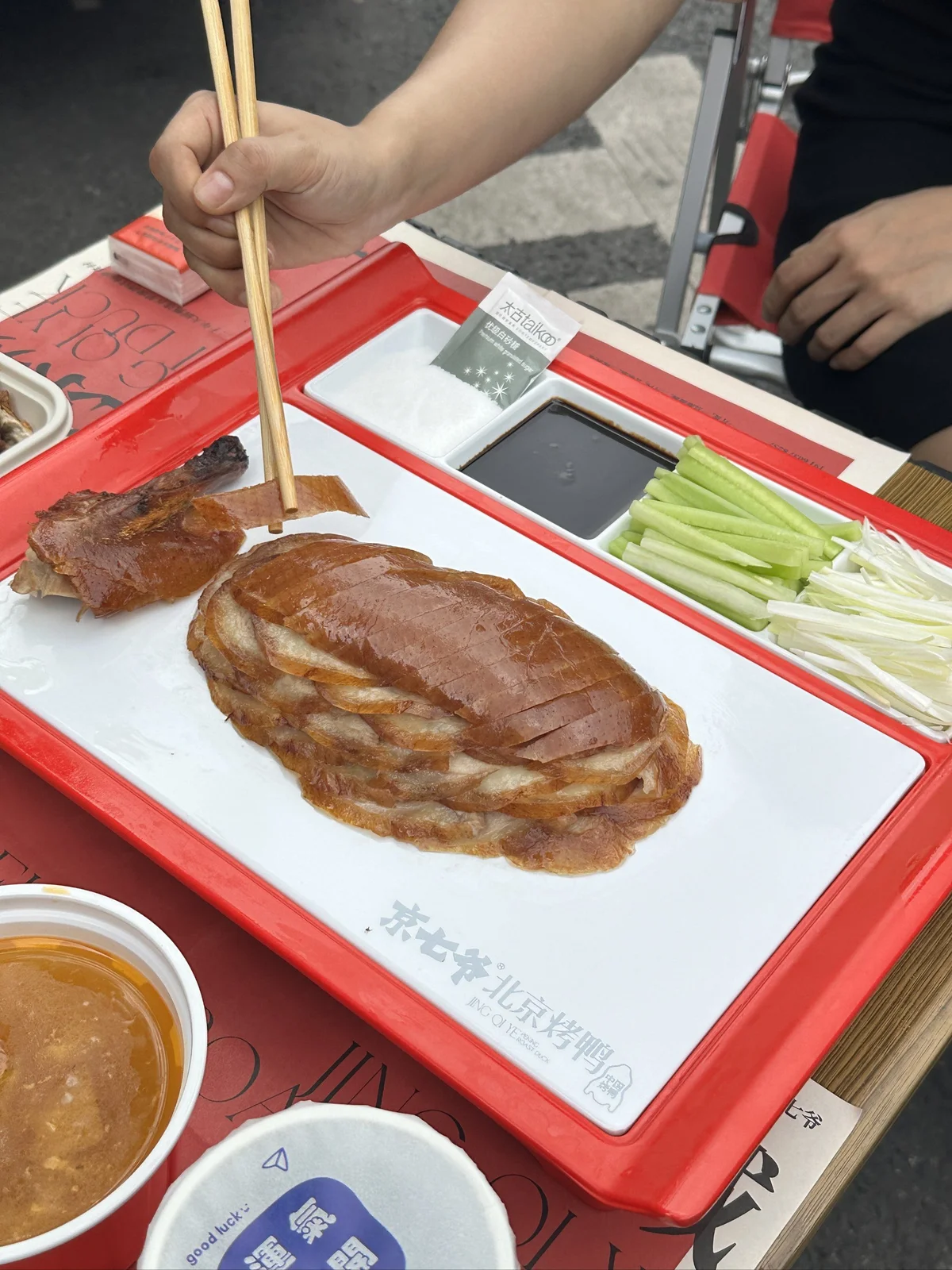 Sliced Peking Duck arranged on a serving plate with crispy skin, cucumber, scallions, sweet bean sauce, and traditional accompaniments that highlight the classic Beijing serving style.
