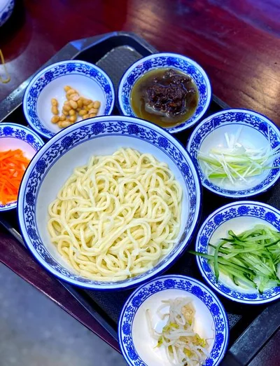 Beijing Zhajiang Noodles set with fresh shredded vegetables and glossy fried soybean paste.