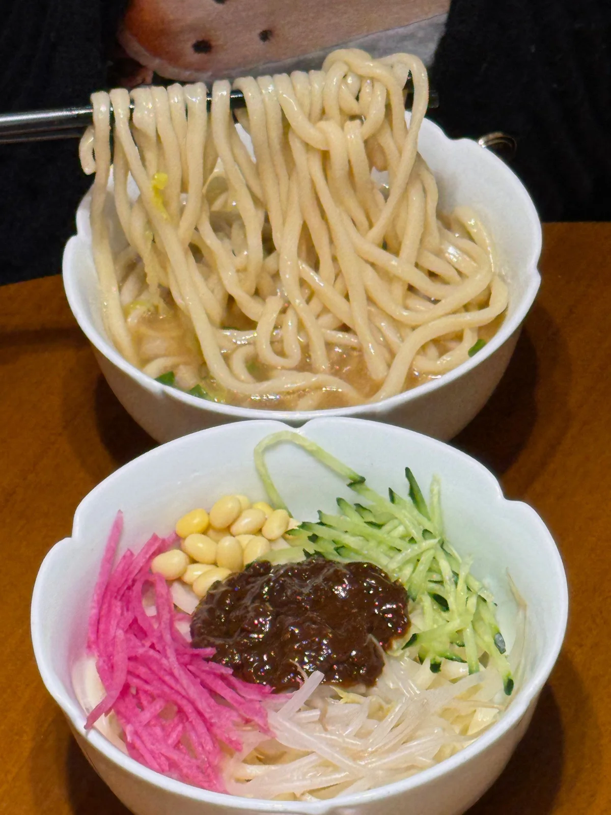 Beijing Zhajiang Noodles with hand-cut noodles and assorted fresh toppings ready to mix with fried soybean paste.