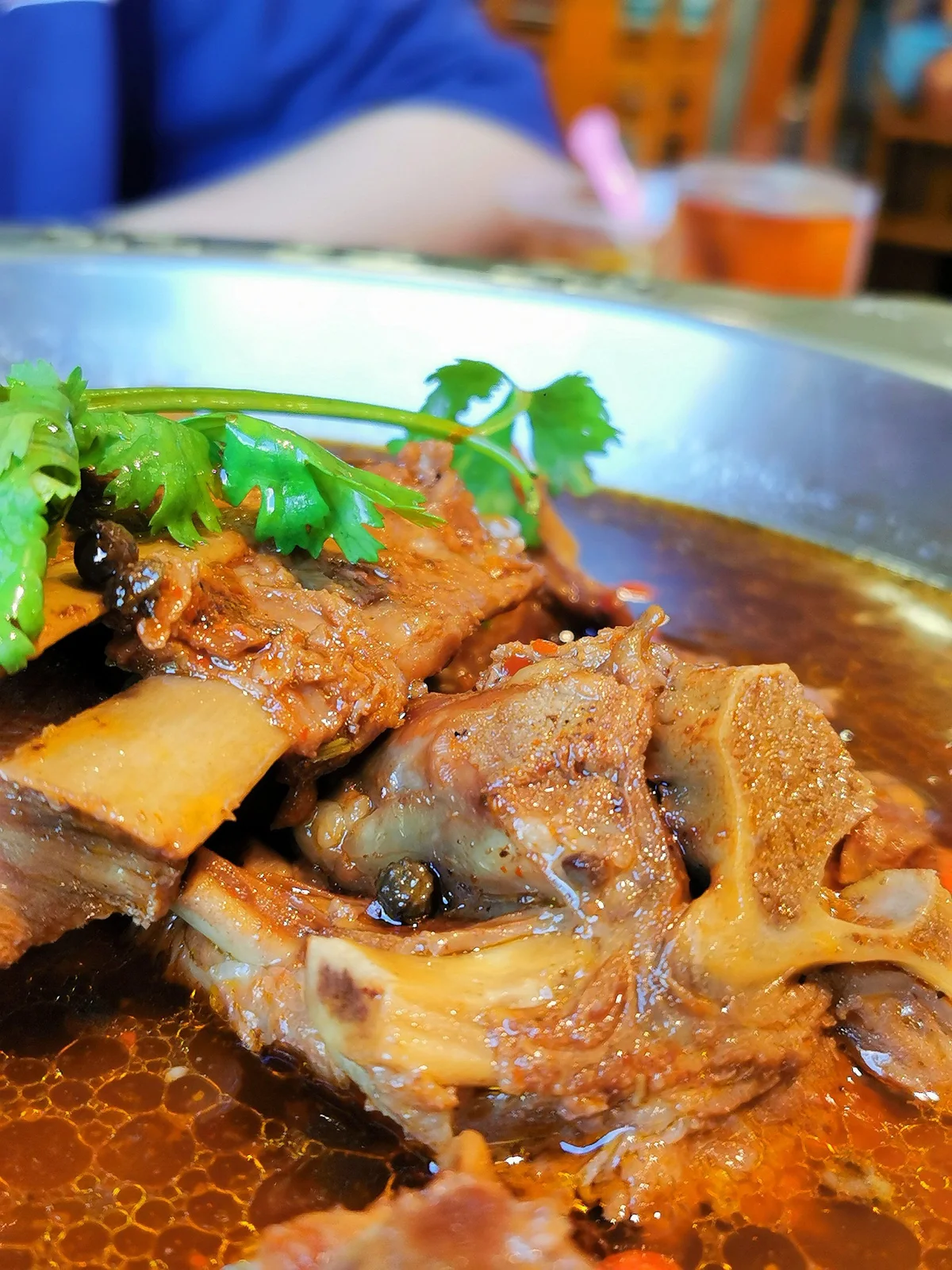 Close-up of tender lamb spine pieces simmering in a rich, aromatic broth infused with spices, herbs, and natural lamb marrow.