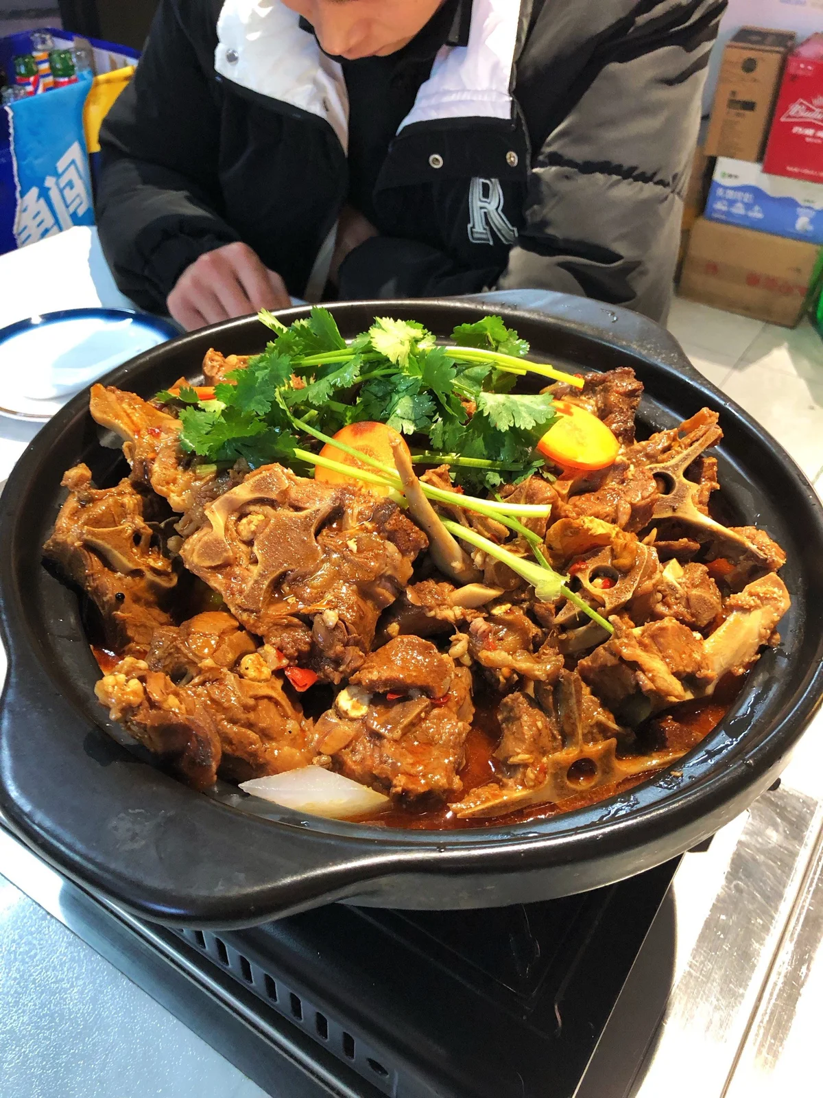 Spicy Beijing lamb spine hotpot served in a cast-iron pot, loaded with tender lamb spine pieces, chili peppers, and cilantro for a bold, warming flavor.