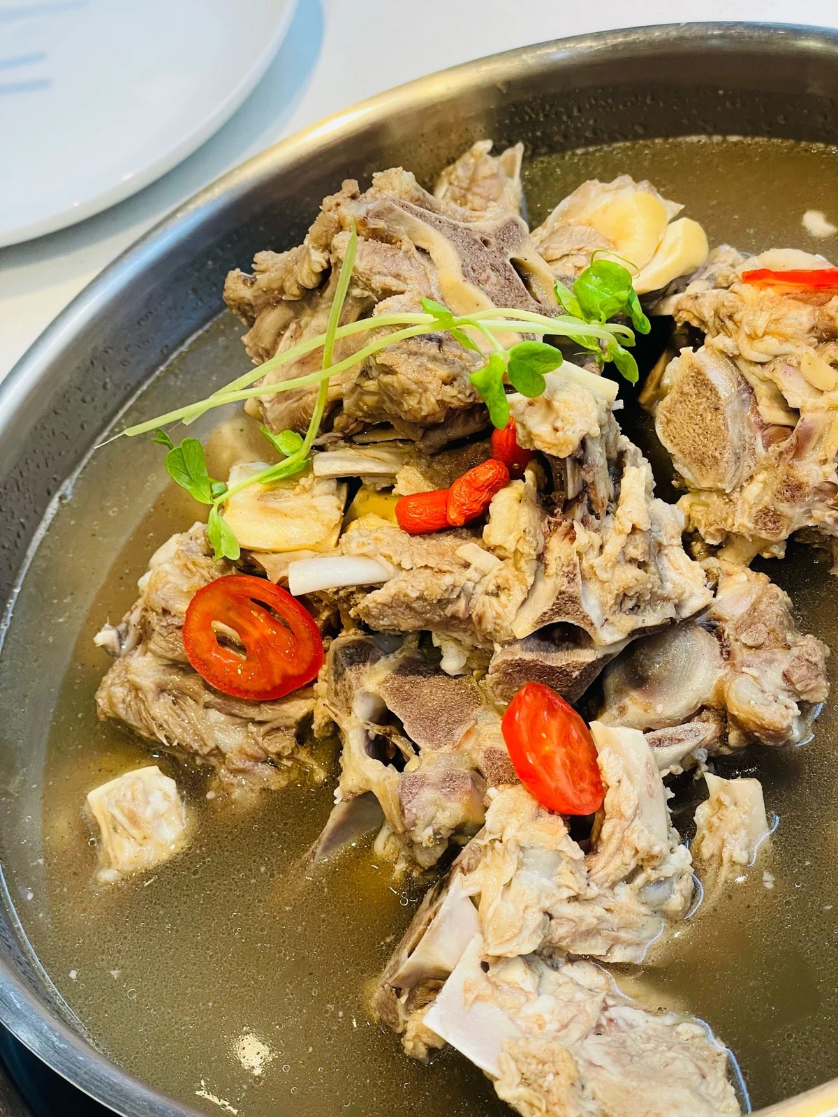 Light broth lamb spine hotpot featuring clean-simmered lamb bones, goji berries, and fresh herbs, highlighting the natural flavor of lamb spine marrow.