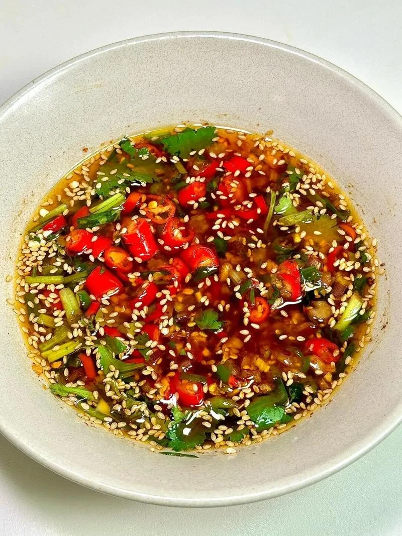 A bowl of Beijing-style dipping sauce for lamb spine hotpot, mixed with chili, cilantro, sesame, and aromatics.