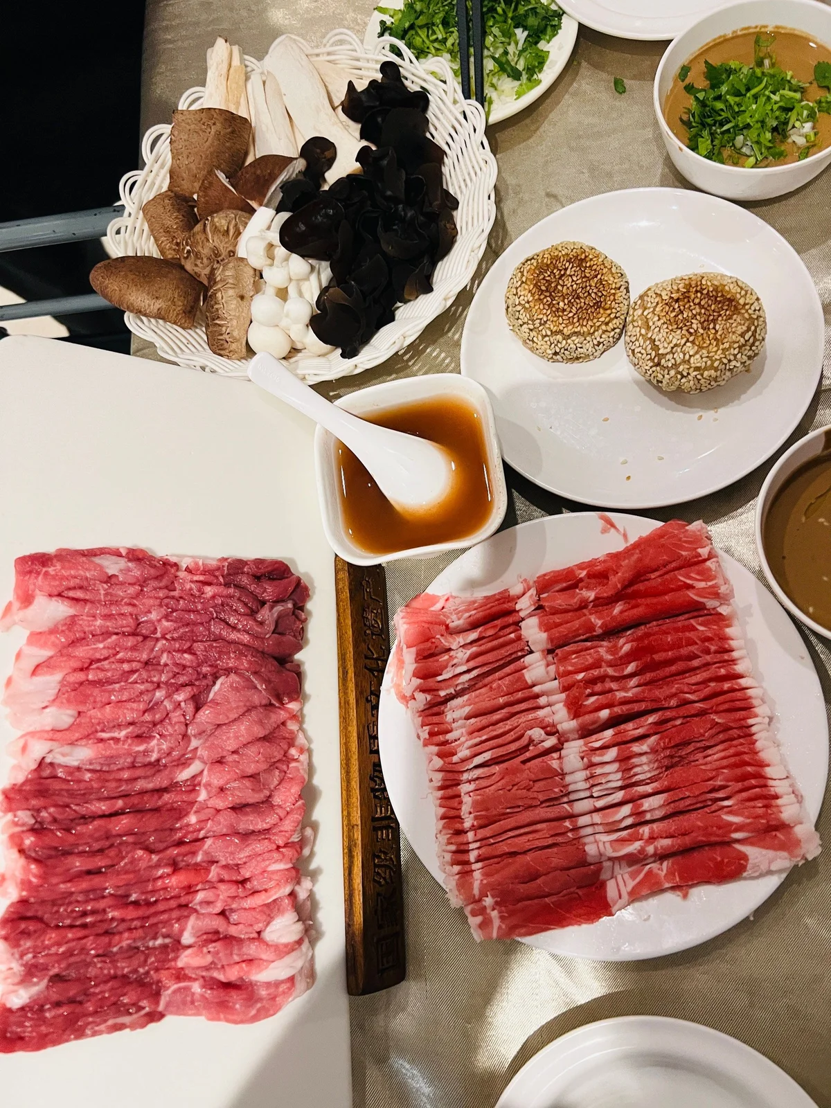 Variety of fresh mushrooms, vegetables, and thinly sliced lamb arranged for a classic Beijing-style shabu shabu hotpot meal.