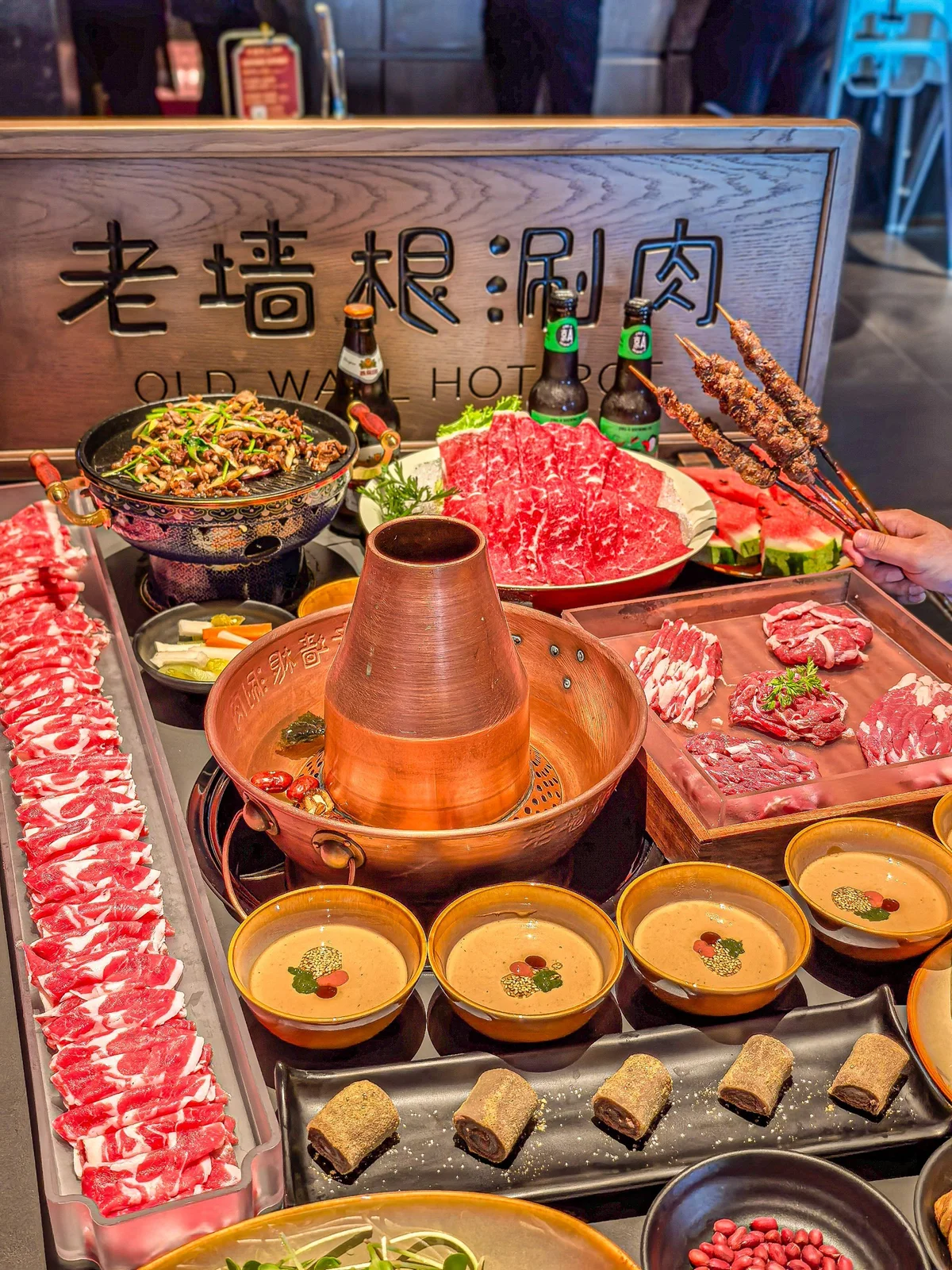 Copper charcoal hotpot paired with assorted lamb cuts, side dishes, and sesame dips, capturing the essence of traditional Beijing instant-boiled mutton.