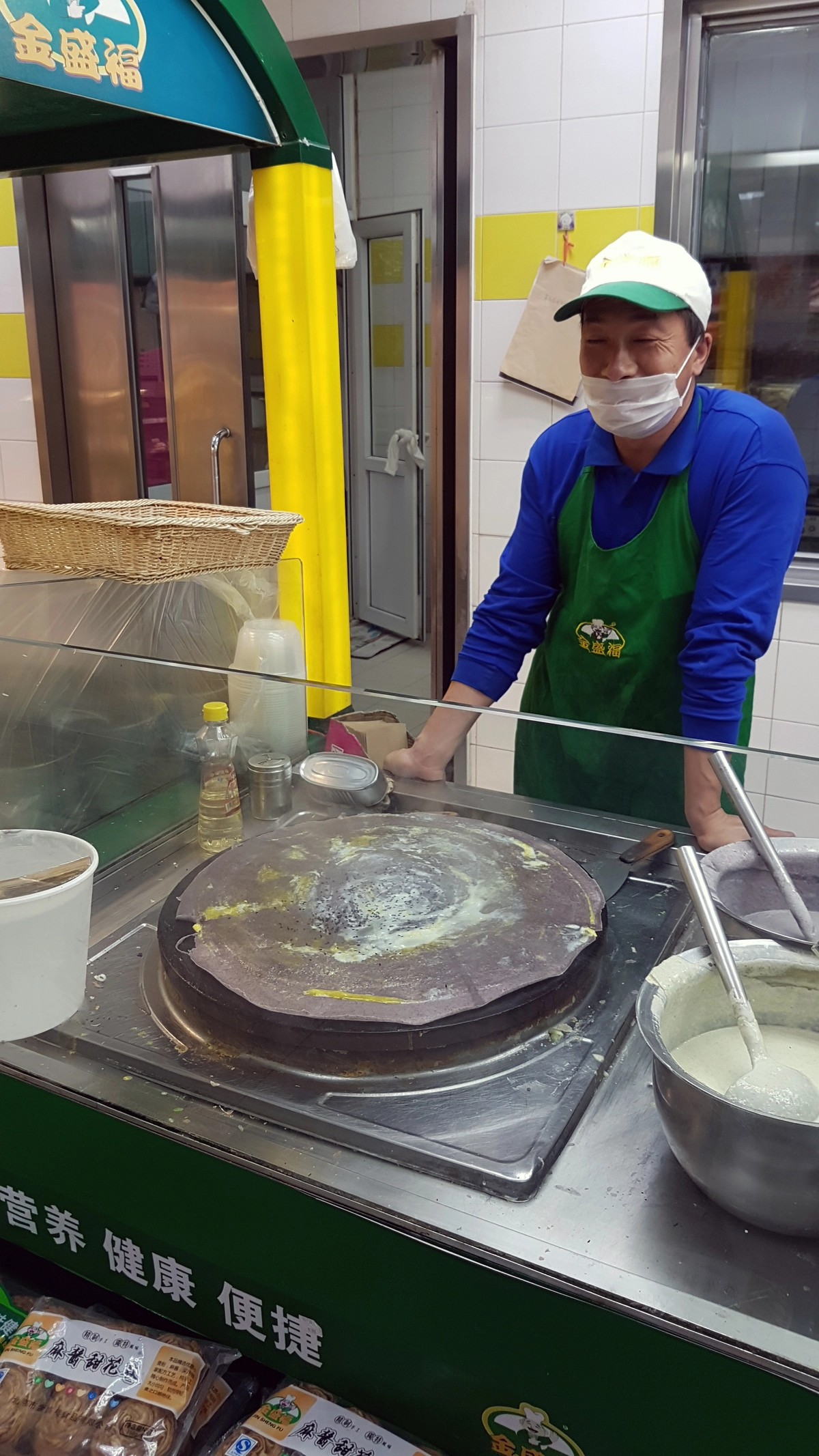 Beijing jianbing vendor spreading batter at a street breakfast stall