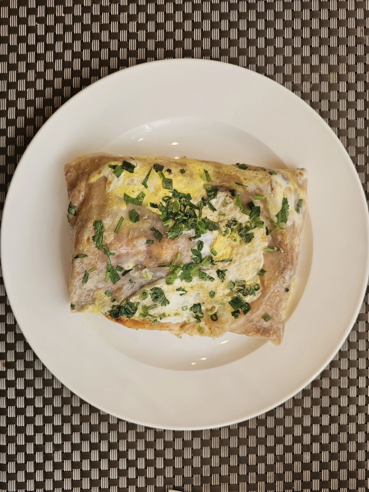 Folded jianbing on a plate showing egg, scallion, and crisp layers
