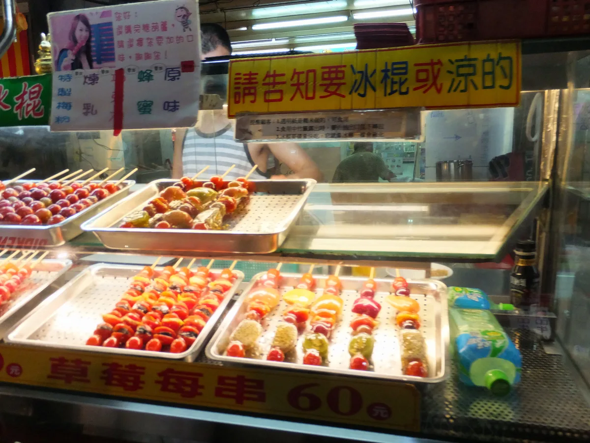 Tanghulu and mixed candied fruit skewers displayed at a snack stall