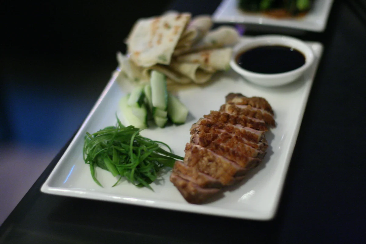 Peking duck slices served with pancakes, cucumber, scallions, and dipping sauce