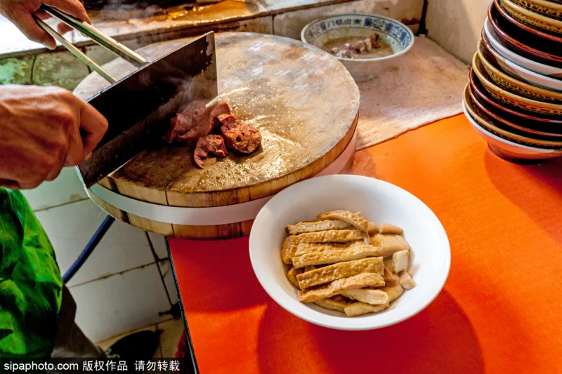 Close bowl of luzhu huoshao with dark broth, tofu, and chopped bread.