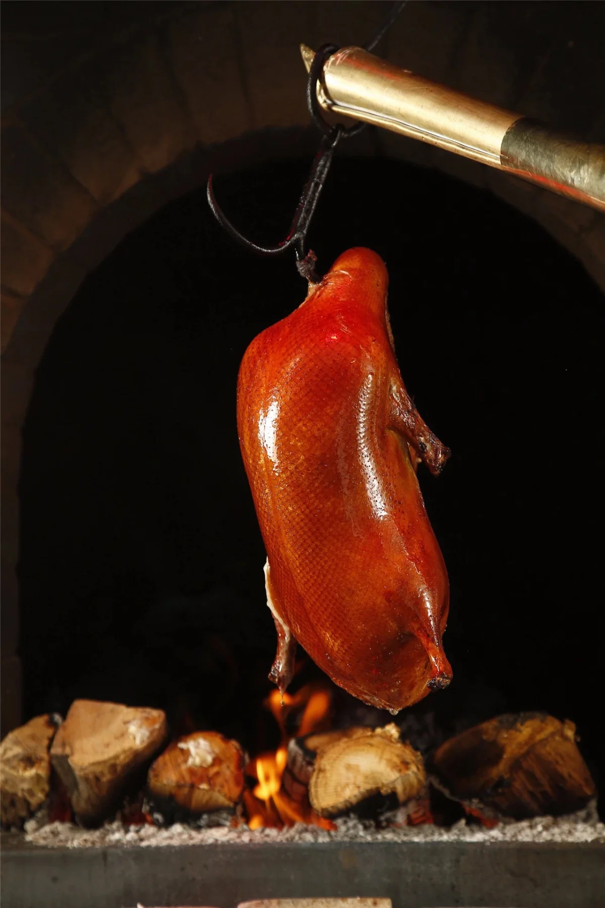 Whole Peking duck roasting in a hanging oven over fruit wood fire