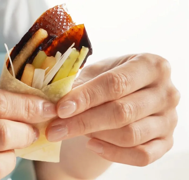 Peking duck wrapped with scallions and cucumber in a thin pancake