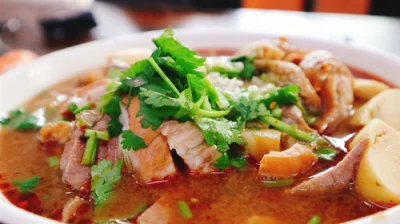 Close-up of Beijing luzhu huoshao with cilantro, broth, tofu, and braised offal