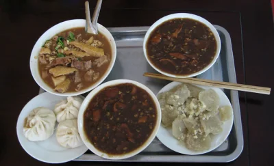 Tray of Beijing breakfast dishes with bowls of chaogan and steamed baozi