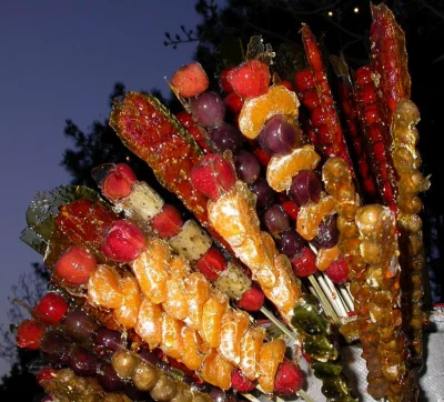 Mixed-fruit tanghulu skewers showing a hard clear sugar shell