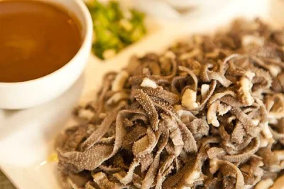 Close-up of Beijing baodu tripe with dipping sauce and chopped herbs