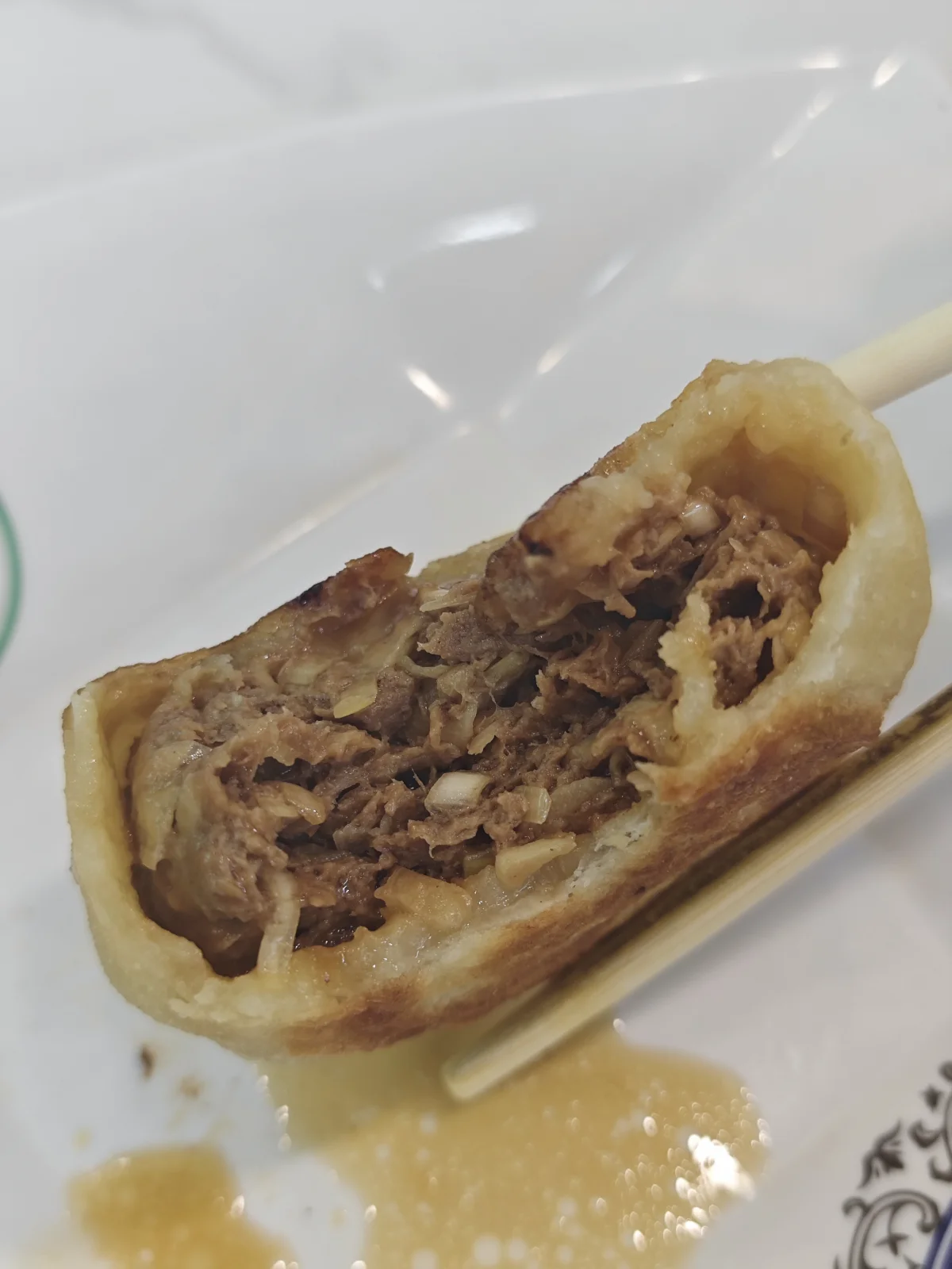 Bitten men ding rou bing showing juicy meat filling inside the Beijing door-nail pie