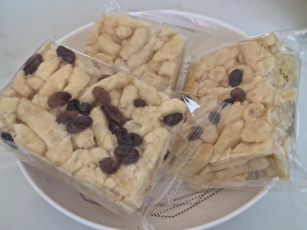 Individually wrapped saqima bars with visible crisp wheat strands and raisins