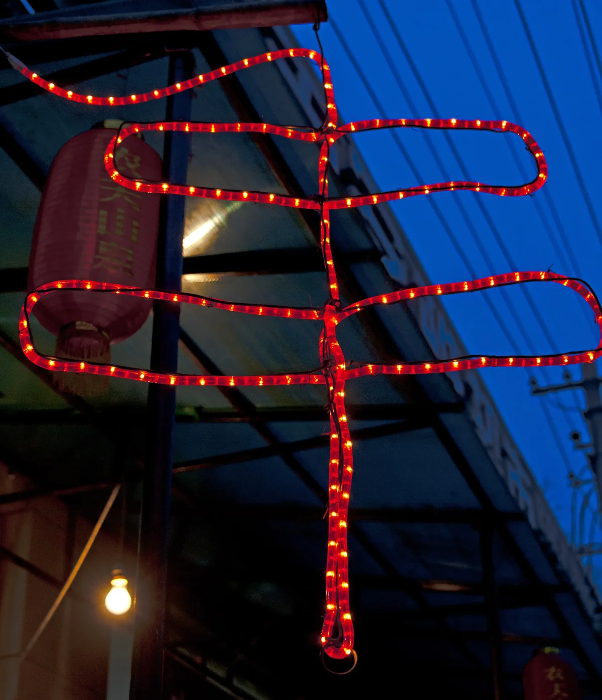 Red LED chuanr sign outside a Beijing shop at dusk