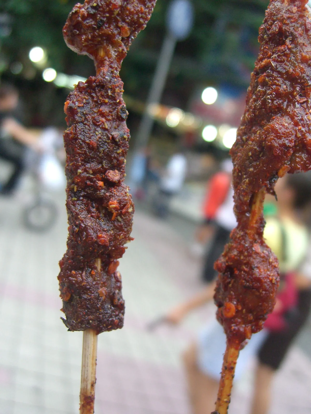 Close-up of grilled lamb skewers with a dark, spiced surface
