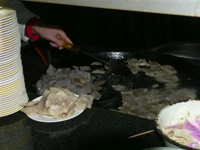 Guanchang slices frying on a flat pan during preparation