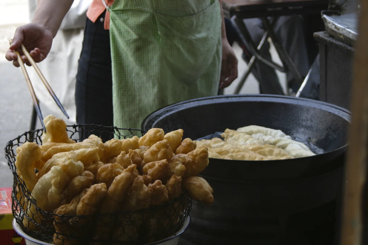 Fresh youtiao frying in hot oil during preparation