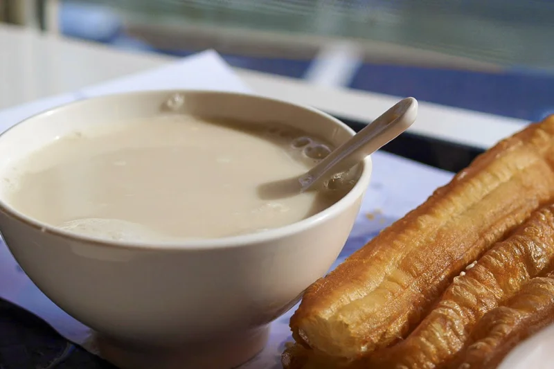 Golden youtiao served with a bowl of soy milk, a classic fried-dough breakfast combination.