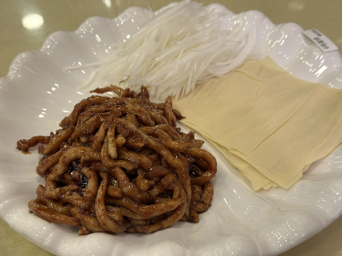 Jing Jiang Rou Si plated with tofu skin sheets and fresh scallion, ready for wrapping.