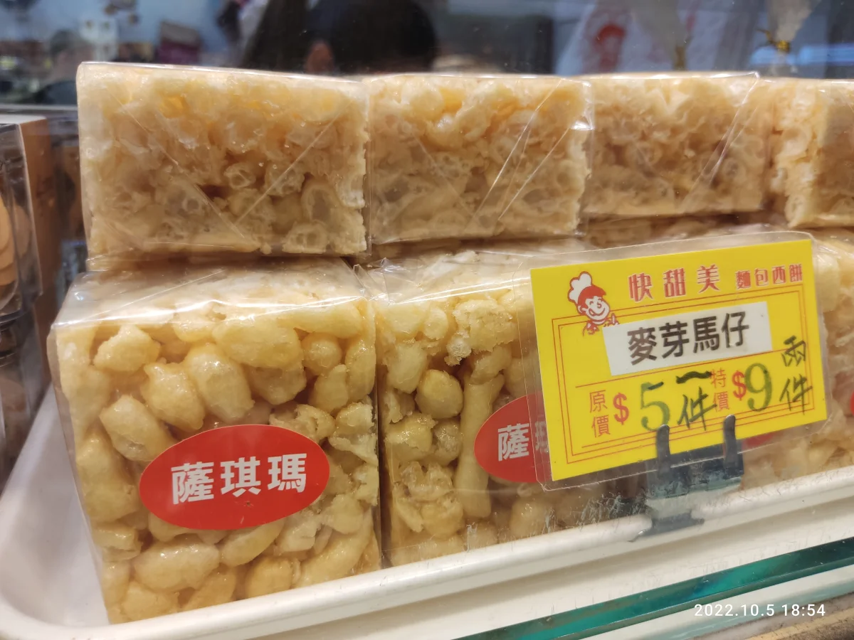 Loose golden sachima squares displayed at a pastry counter, showing the light fried-dough structure.