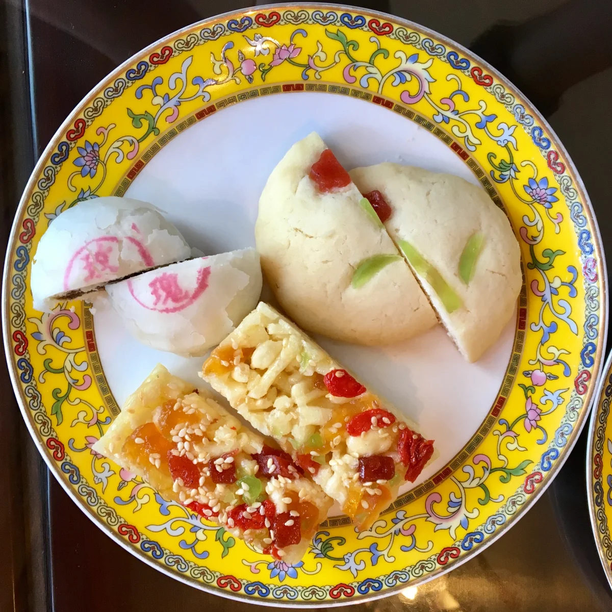 A small piece of sachima served among other traditional pastries on a shared plate.