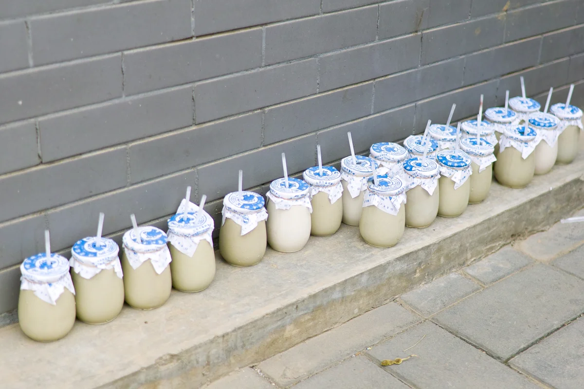 Small ceramic jars of old Beijing yogurt lined up on a Beijing street-side counter.