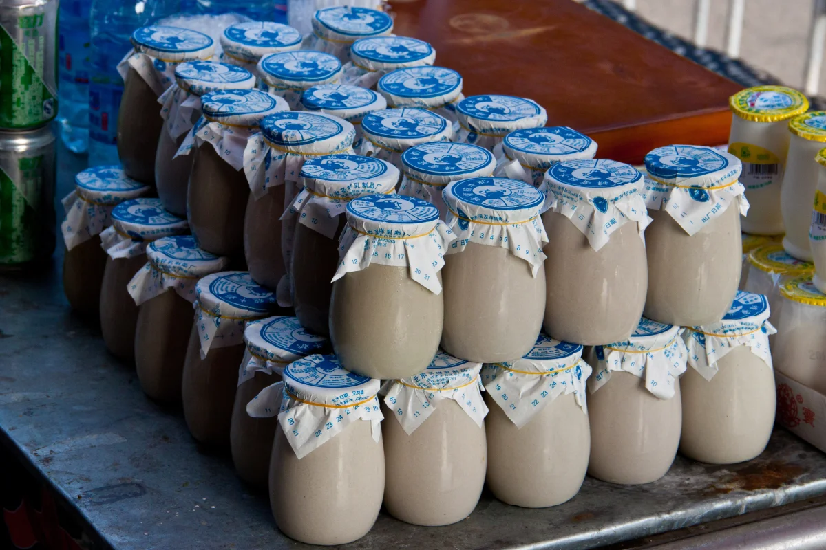 Stacked ceramic yogurt jars with blue paper lids at Wangfujing Food Market in Beijing.