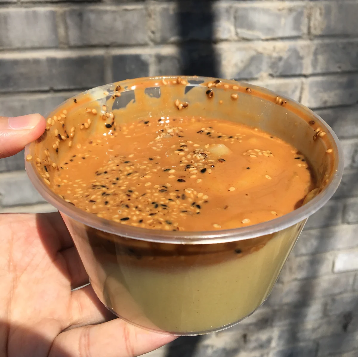 A cup of Beijing miancha topped with sesame paste and toasted sesame seeds