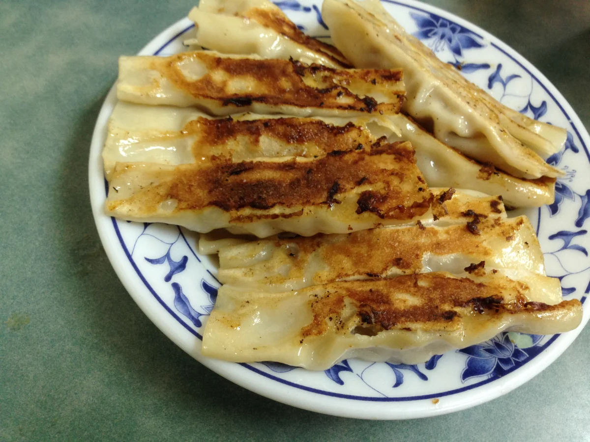 Elongated potstickers with browned bases on a blue-and-white plate, photographed in Taipei