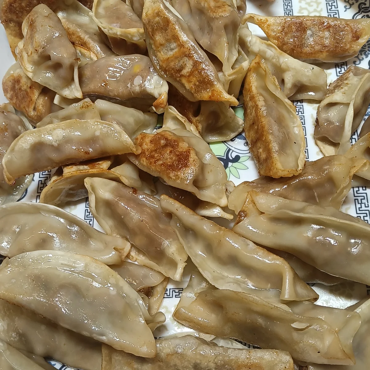 Beef-and-corn potstickers with golden pan-fried bases on a patterned plate