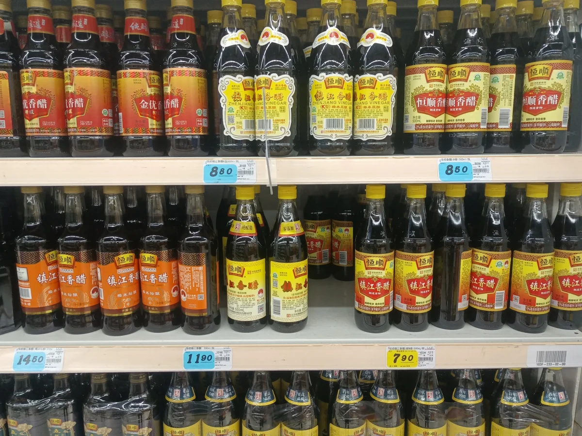 Bottles labelled Zhenjiang aromatic vinegar on a shop shelf; historical photograph, not current prices