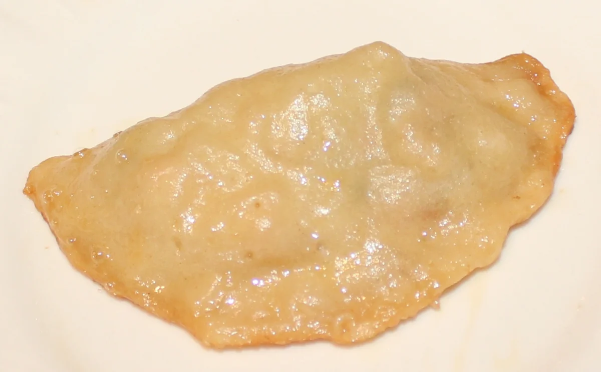 A pan-fried Chinese vegetable potsticker on a white plate