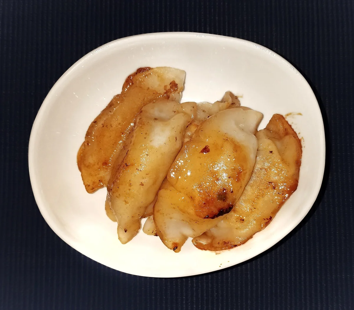 A plate of browned potstickers served with sauce in Massachusetts