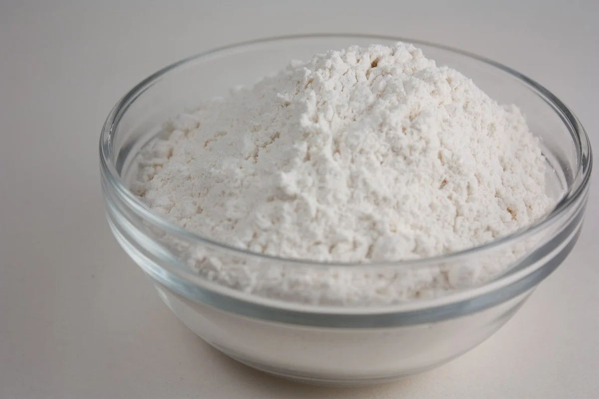 Wheat flour in a glass bowl, a common base ingredient in Beijing-style saqima