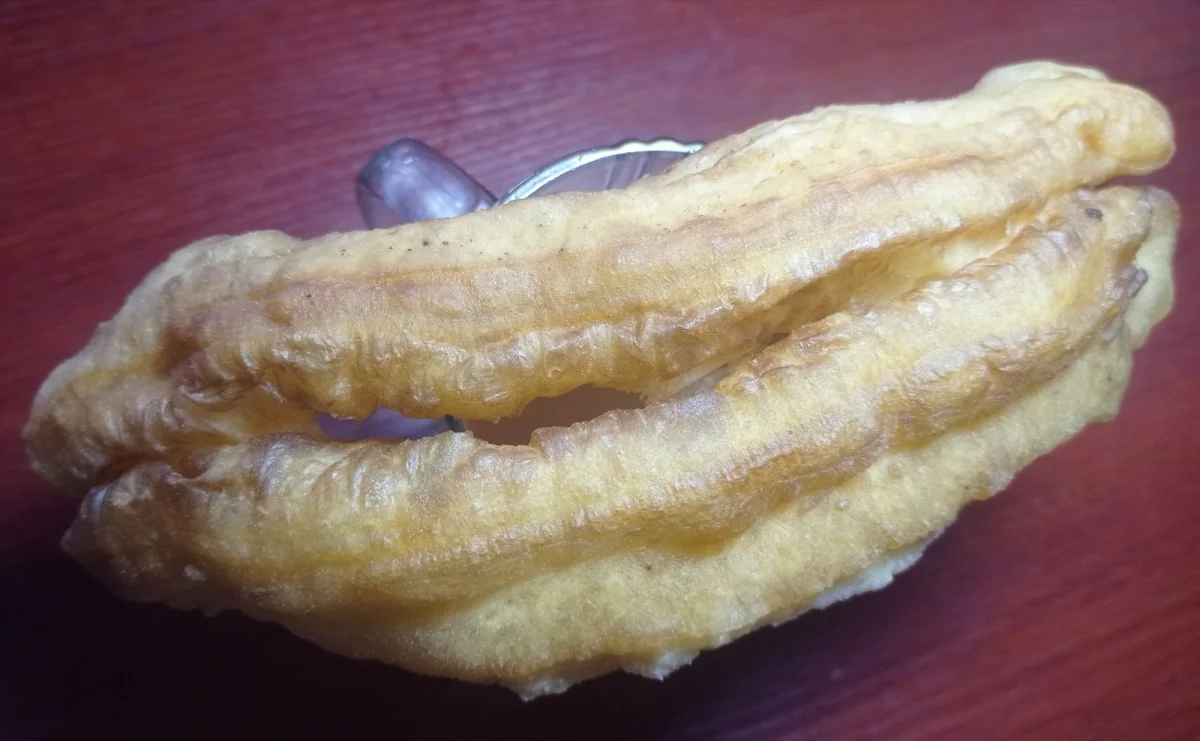 An individual youtiao showing its inflated shape; a photograph from the Myanmar food context, not a Beijing venue